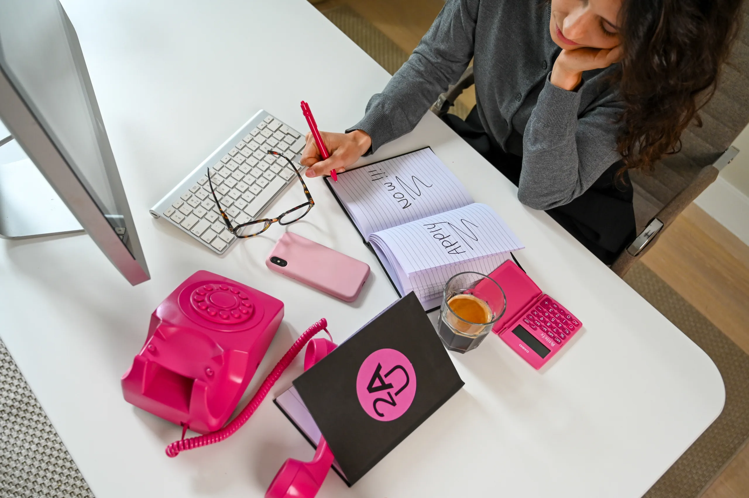 Een vrouw die achter haar bureau zit met allemaal spullen.