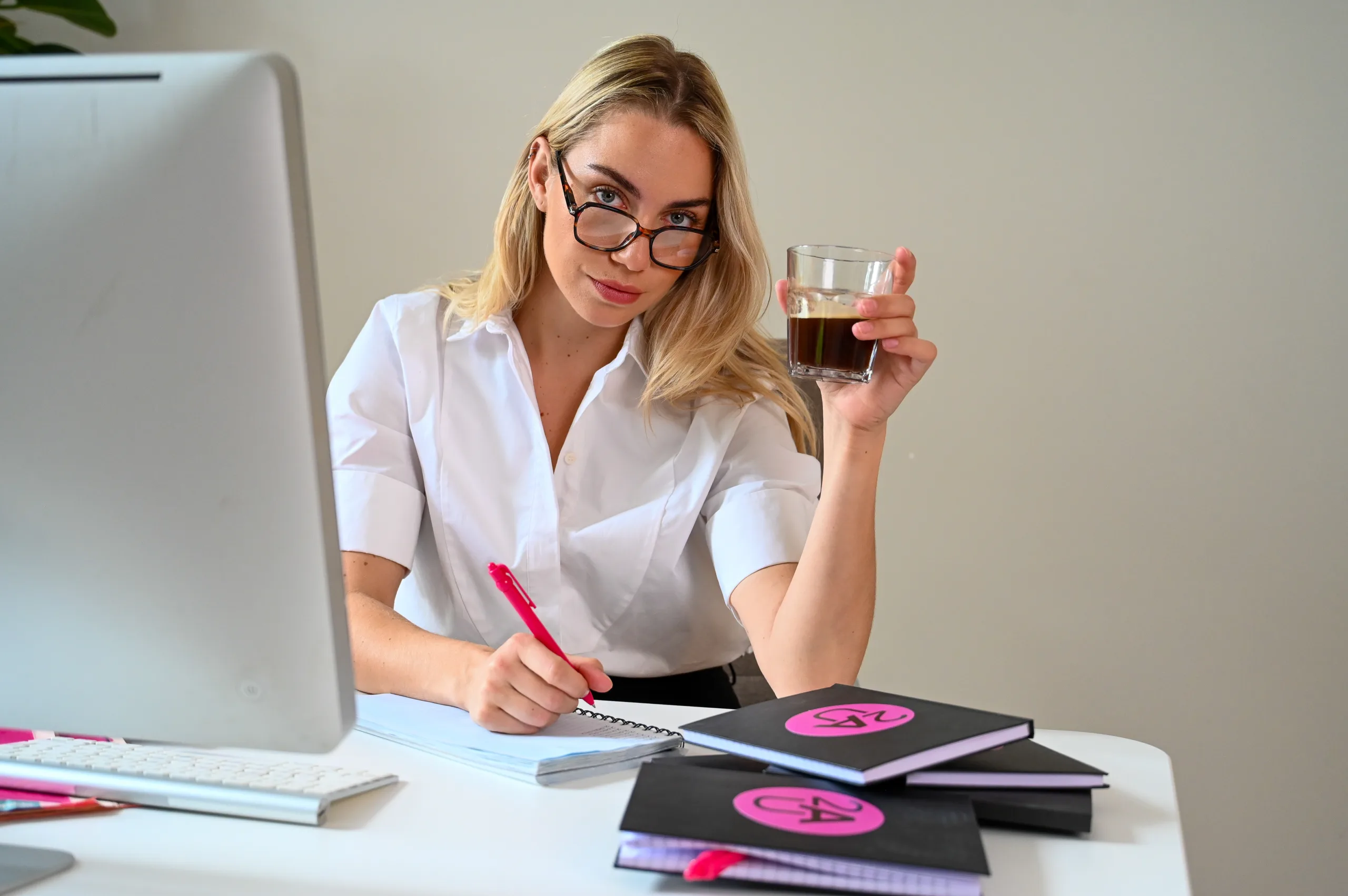 Een vrouw werkt achter haar computer en maakt aantekeningen